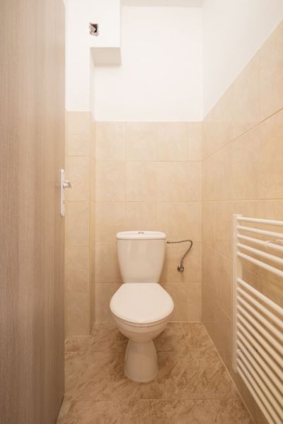 Toilet in a family house with tiles and a heating ladder.