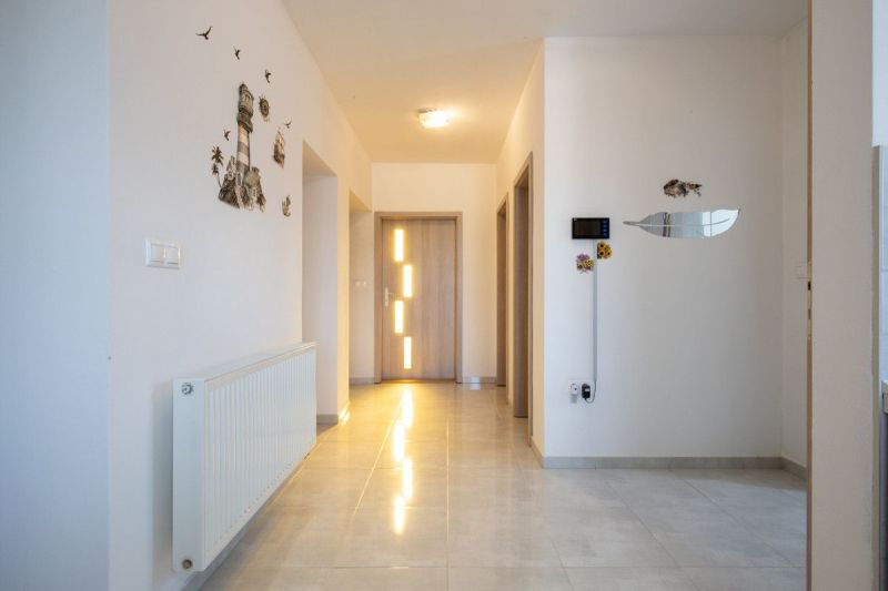 A hallway in a family house with white walls, a radiator, and decorations.