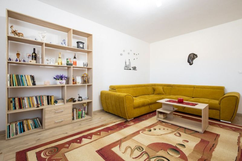 Living room in a family house with a library, yellow sofa, and carpet.