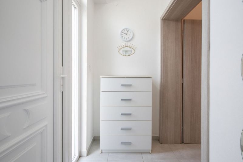 Interior of a family house with a white dresser, clock, and mirror on the wall.