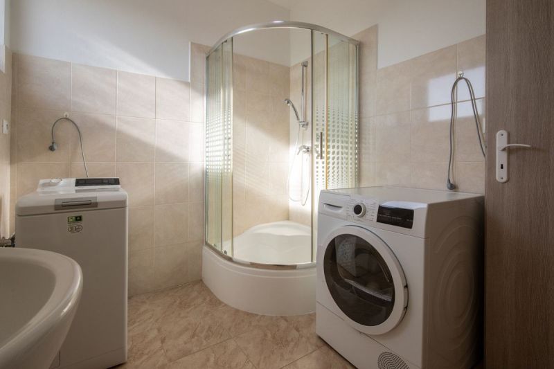 Bathroom with a washing machine and a shower in a family house, floor with wooden decor.