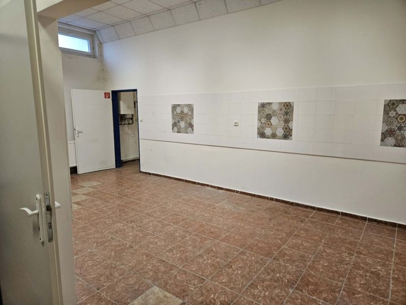 The interior of commercial spaces with tiled floors and white walls with patterned tiles.