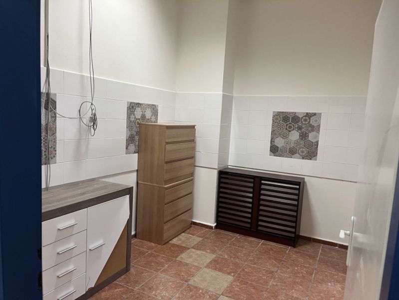 Commercial space with white walls, furniture, and ceramic tiles on the floor.