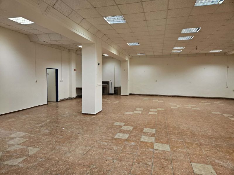 Interior of a commercial space with tiled flooring and ceiling lighting.