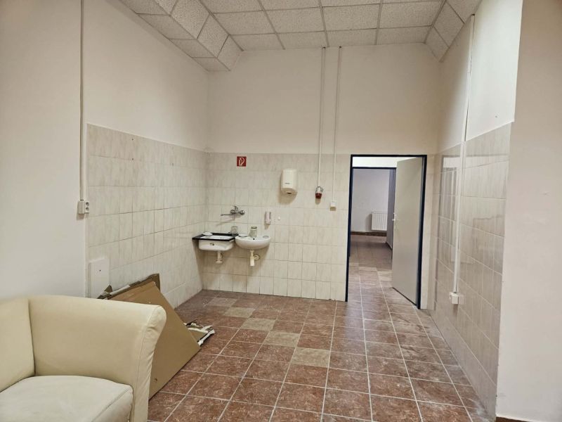 Interior of commercial spaces with sinks, tiles, and a light-colored armchair.