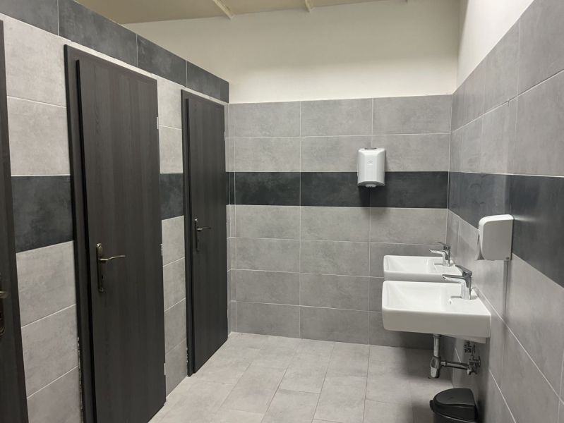 Restrooms in commercial spaces with sinks and doors for separate stalls.
