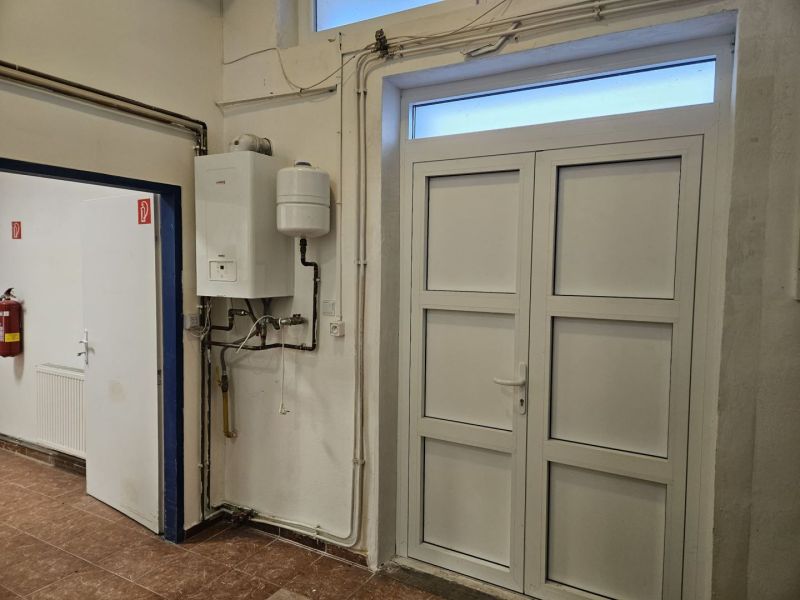 White boiler on the wall of commercial premises with a wooden decor floor.