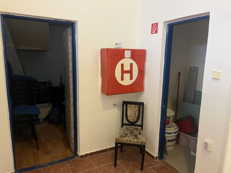 Interior of commercial premises with a fire cabinet, a chair, and storage rooms.