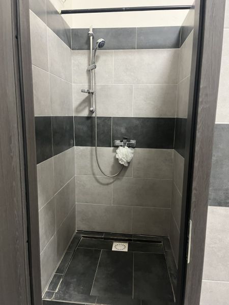 A shower corner with black and gray tiles in commercial premises.