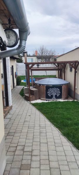 The courtyard of a family house in Dolný Štál with a hot tub under a pergola and a manicured lawn.