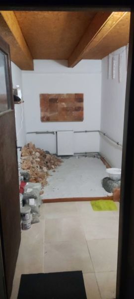 A room in a family house with tiles, stored building materials, and a radiator.