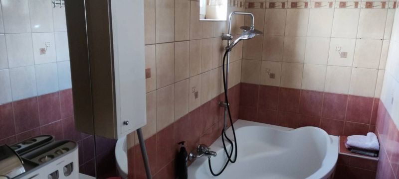 Family house bathroom with a bathtub, shower, and tiles in warm tones.