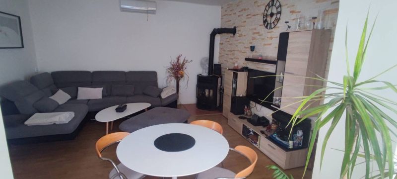 Living room in a family house with a wood-patterned floor, a sofa set, and a table.