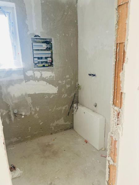 The interior of a family house with a distribution board and raw walls, showing the preparation of electrical installation.