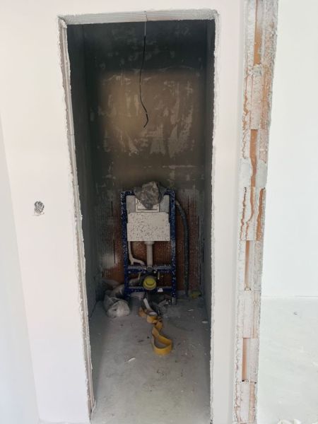 Space for installing a toilet in a family house with unfinished walls and floor.
