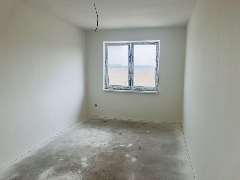Empty room with gray floor, window, and white walls in a family house.