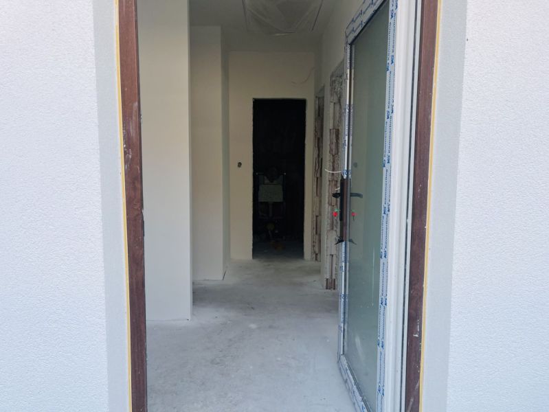 A view into the hallway of a family house with a raw concrete floor.