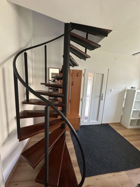 Spiral staircase in a studio apartment with a wood-patterned floor.