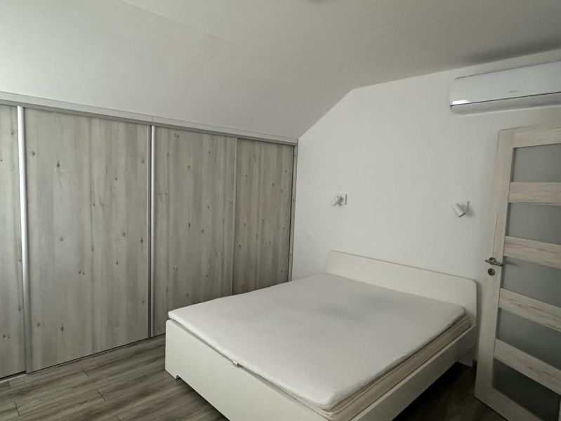 Bedroom in a studio apartment with a white bed and a built-in wardrobe.