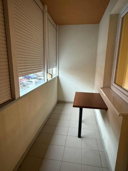 Closed terrace with cladding, folding table, and view from a three-room apartment.