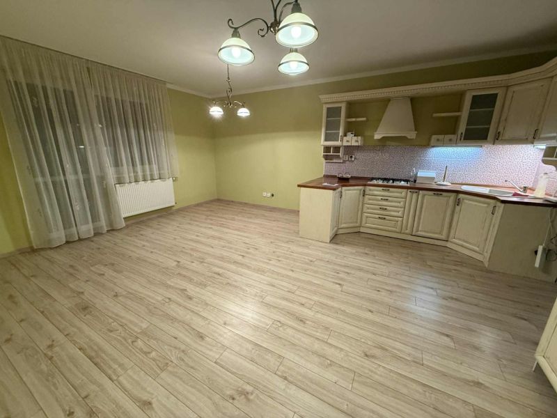 A kitchen in a 3-room apartment with a wooden decor floor and light fixtures.