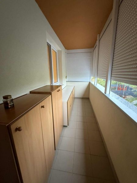 Enclosed loggia in a 3-room apartment with tiles and wooden cabinets.