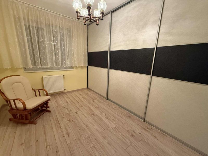 A room in a 3-room apartment with a wooden decor floor, an armchair, and a wardrobe.