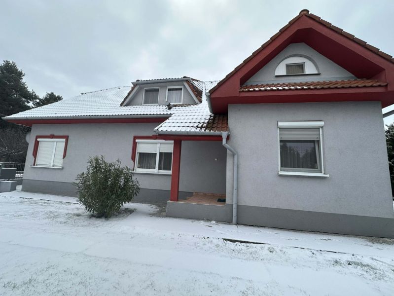 A family house in Dolný Štál with red window frames and a snow-covered roof.