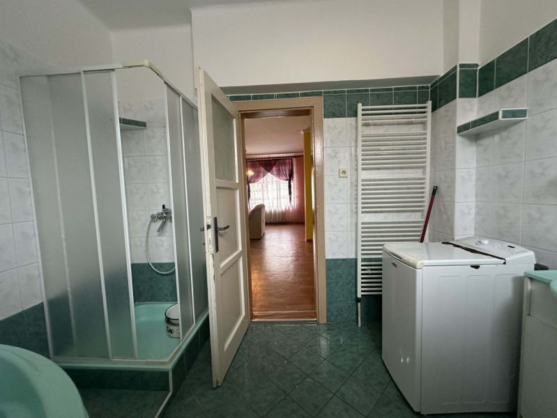 Bathroom with a washing machine and a shower in a family house.