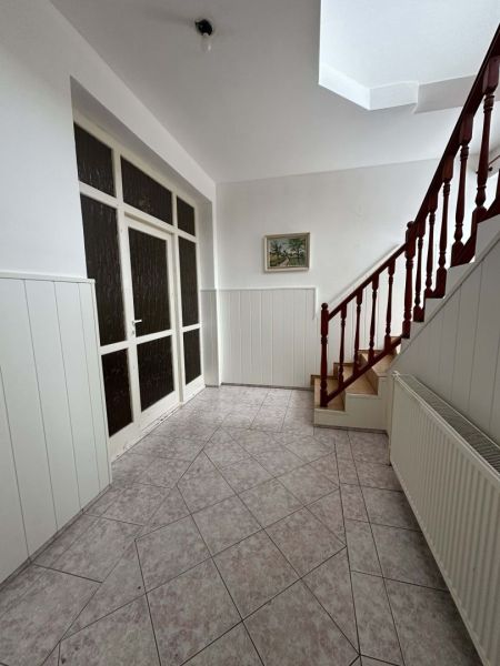 A hallway with tiles and a wooden staircase in a family house.