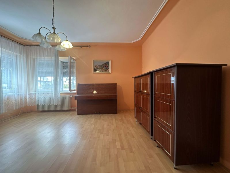 Living room in a family house with a piano and furniture, floor with wooden decor.