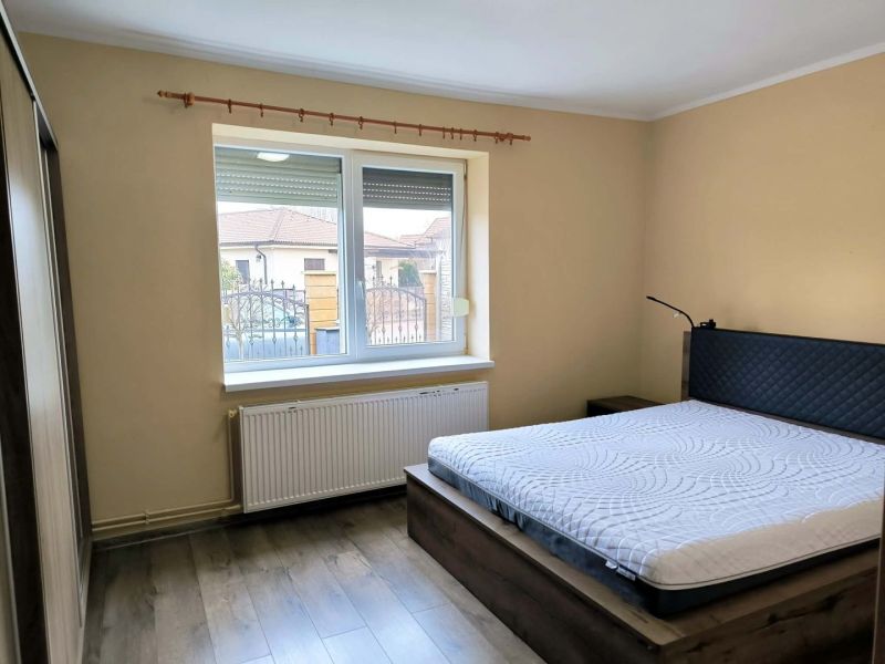 Bedroom in a family house with a wood-patterned floor and a large window.