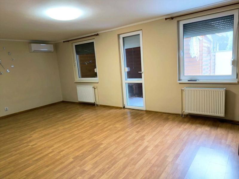 A spacious room in a family house with a wooden decor floor and windows.