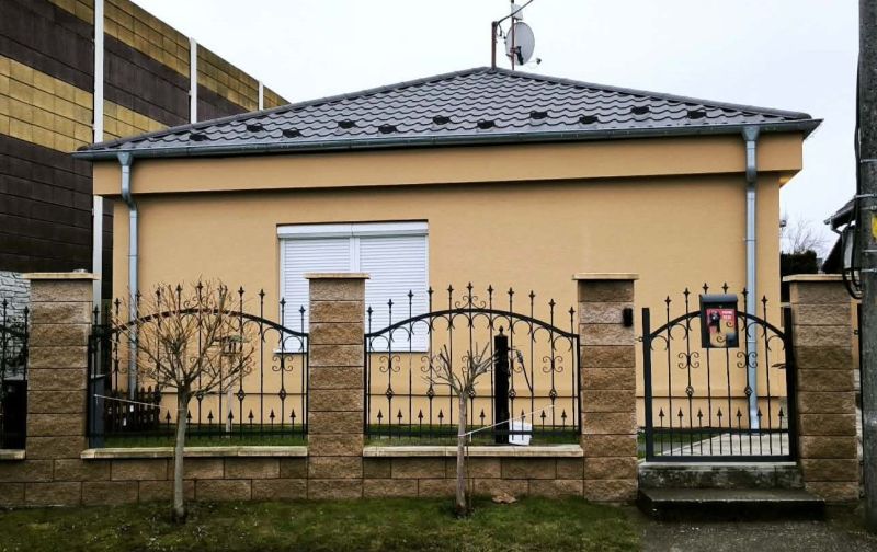 A family house in Ohrady with a stone fence and a satellite dish on the roof.