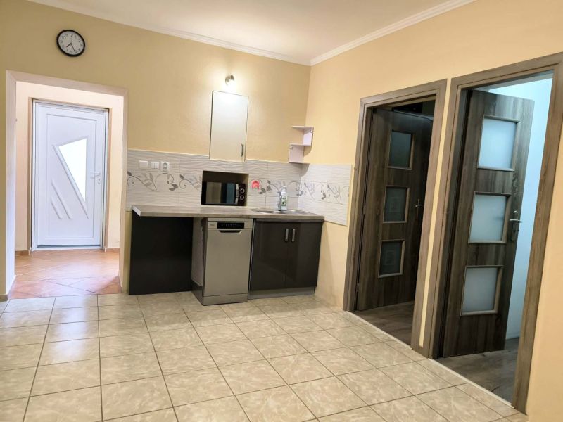 A kitchen in a family house with light-colored tiles and a kitchen unit with a microwave.