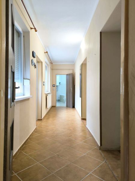 A hallway in a family house with ceramic tiles and light-colored walls.