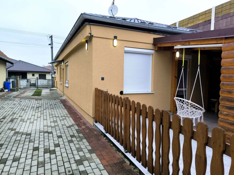 A family house in Ohrady with a courtyard, fencing, and a hanging swing by the side entrance.