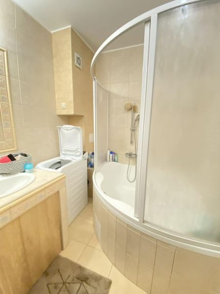 A bathroom in a 3-room apartment with a corner bathtub and a washing machine.