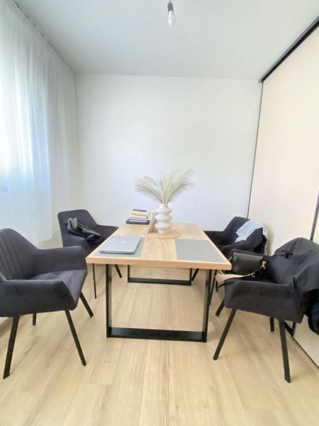 Dining table with black chairs and wooden decor flooring in a 3-room apartment.
