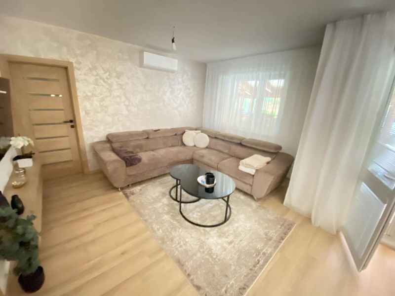Living room in a 3-room apartment with a sofa, wood-patterned flooring, and curtains.