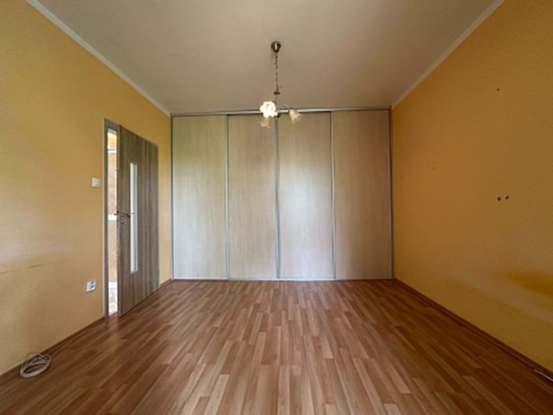 A room in a one-room apartment with a wooden decor floor and built-in wardrobes.