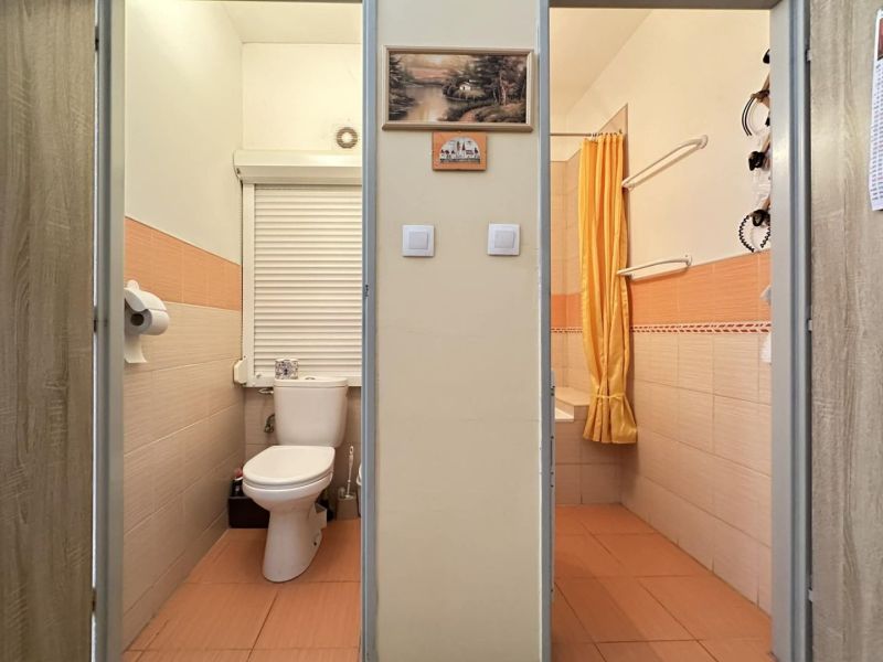 Bathroom in a studio apartment with orange tiles and a curtain.
