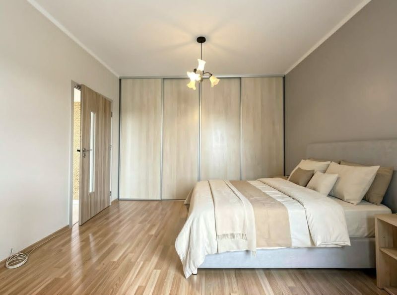 Bedroom in a studio apartment with a bed and a wooden decor floor.