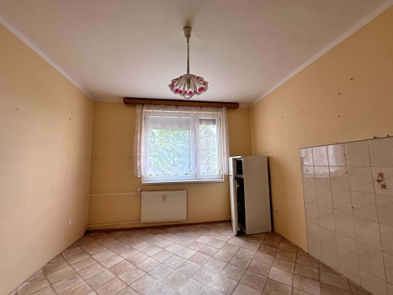 A room with tiles, bright walls, a radiator, and a pendant light.