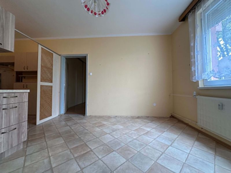 Interior of a 1-room apartment with a beige wall and tiled floor.