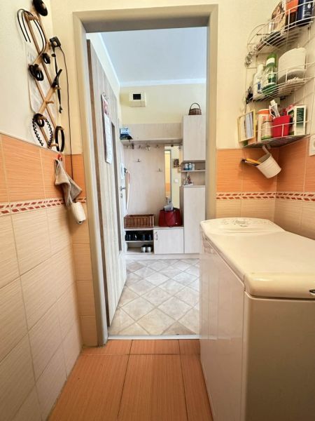 A bathroom in a studio apartment with a washing machine and storage shelves.