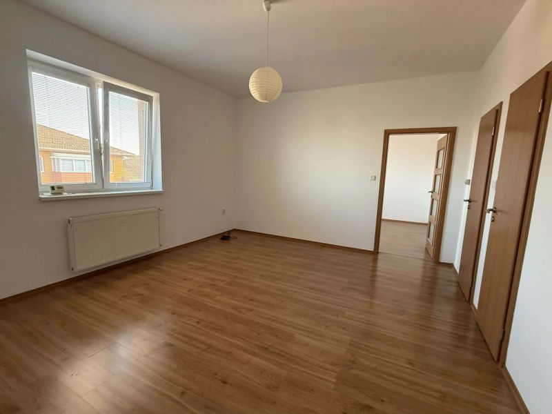 A room in a 3-room apartment with a wood-patterned floor and a large window.