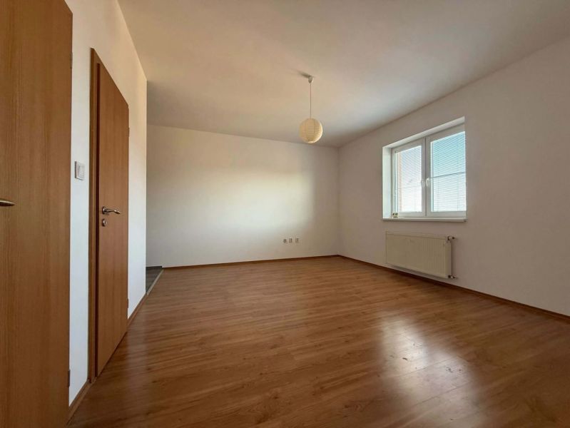 A room in a 3-room apartment with a wood-patterned floor and a large window.