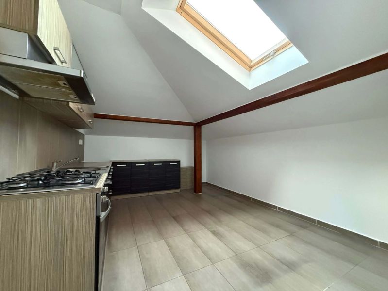 A kitchen in a 3-room apartment with a skylight and a wooden decor floor.