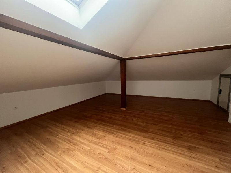 An attic room with a wooden decor floor and a skylight in a 3-room apartment.